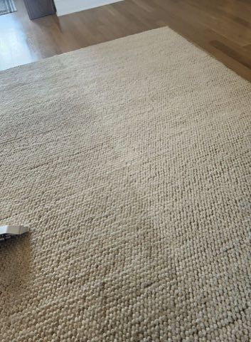 Natural-fiber entry runner rug on a hardwood floor showing a before-and-after cleaning line