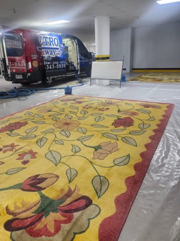 Large yellow floral hand-hooked area rug cleaned beside the Metro Steamway van
